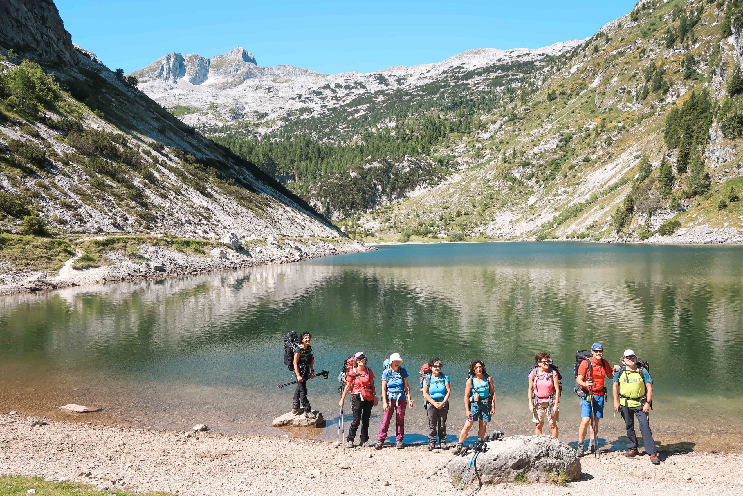 Hikers enjoying a short stop by one of the seven lakes in the Seven lakes valley on the way to Triglav.